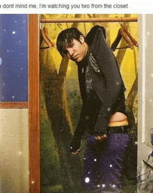 a man is standing in front of a closet with clothes hanging on it