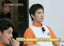 a man in an orange and white shirt is eating a snack