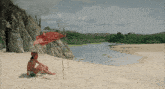 a man sits on a sandy beach with a red flag in the background