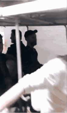 a group of people are sitting in a room . one of the men is wearing a hat .