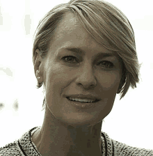 a close up of a woman 's face smiling and wearing earrings