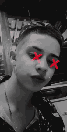 a black and white photo of a young man with red crosses on his face