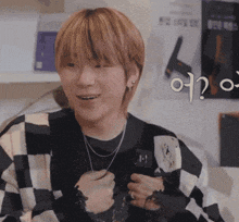 a man wearing a black and white checkered shirt and a necklace is smiling