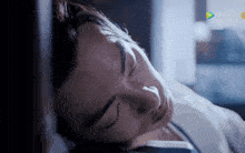 a man is sleeping in a bed with his eyes closed and a chinese advertisement behind him