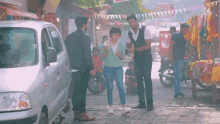 a group of people are standing in front of a car
