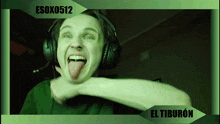 a man wearing headphones is sticking his tongue out in front of a green background that says esox0512 el tiburon