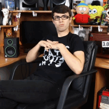 a man wearing glasses and a black shirt that says cats on it