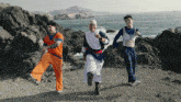 three men in dragon ball costumes are running on a beach