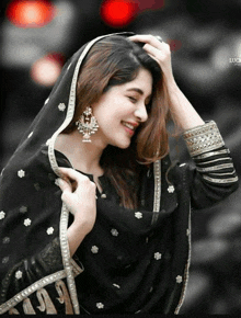 a woman wearing a black dress and a veil smiles for the camera