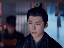a young man with a crown on his head looks at the camera