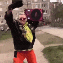 a man in a black jacket and red pants is holding a boombox in his hand