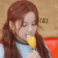 a girl with red hair eating a corn dog