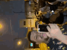 a man is holding a cell phone in his hand while standing in front of a crowd of people .