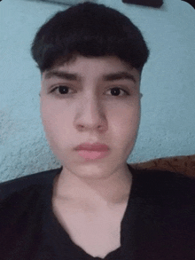 a young man with short hair is taking a selfie while sitting on a couch .