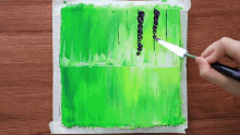 a person is using a spatula to spread green paint on a paper
