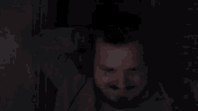 a man is covering his face with his hand in the dark .