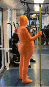 a man in an orange bodysuit is standing on a train