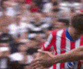 a man in a red and white striped shirt is shaking hands with another man in front of a crowd of people .
