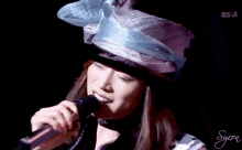 a woman wearing a hat singing into a microphone with bsr written in the corner