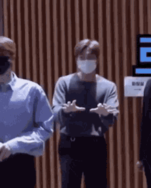 a group of men wearing face masks are standing in front of a wall .
