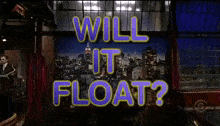 a man in a suit stands in front of a screen that says " will it float "