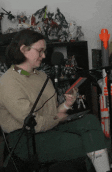 a woman is sitting in front of a microphone and holding a tablet