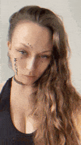 a woman with long hair has a tattoo on her face
