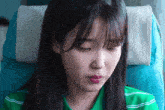 a woman in a green shirt is sitting in a blue chair
