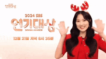 a woman wearing a reindeer headband is smiling and waving in front of the 2024 sbs drama awards sign