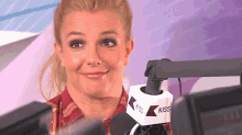 a woman is sitting in front of a kiss radio microphone