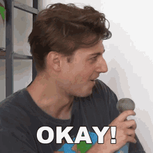 a man holding a microphone with the word okay written on his face
