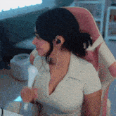 a woman wearing headphones is sitting in a pink chair and holding a remote control
