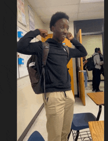 a boy with a backpack is standing in a hallway with a sign on the wall that says ' classroom '
