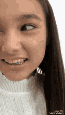 a close up of a girl 's face with braces on her teeth and a white shirt .