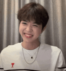 a young man wearing a white shirt with a red heart on it is smiling