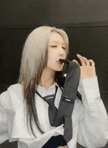 a woman wearing a white shirt and a black tie with a label on it that says ' ncrm '
