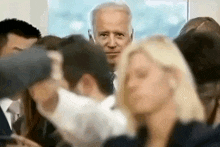 a blurry picture of a man in a suit and tie surrounded by people
