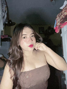a woman wearing a brown strapless top is standing in a dark room