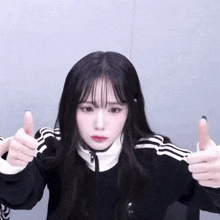 a girl with long black hair is giving a thumbs up sign