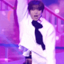 a man in a white jacket and tie is dancing on a stage .