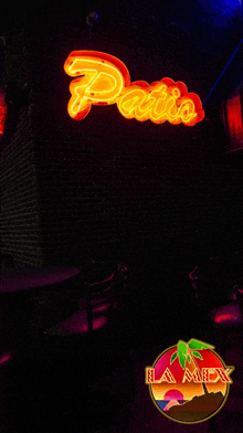 a neon sign that says " patio " hangs above a dark room