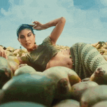 a woman in a crop top is laying in a pile of mangoes
