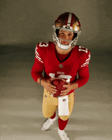 a man wearing a red 49ers jersey holds a football