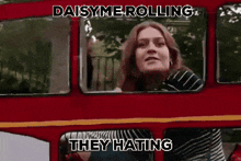 a woman is sitting on a red double decker bus with the words daisy me rolling they hating .