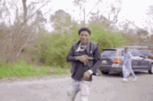 a man is standing on the side of a road holding a gun .