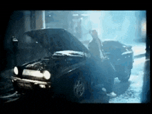 a man is standing next to a broken down car with the hood open .