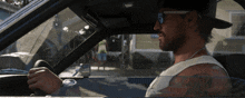 a man wearing sunglasses and a hat driving a car