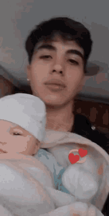 a man is holding a baby in his arms with hearts on it .