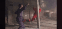 a man in a purple suit and a man in a red suit are fighting each other in a dark room .