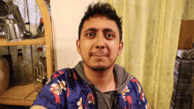 a man wearing a blue shirt with flowers on it is smiling